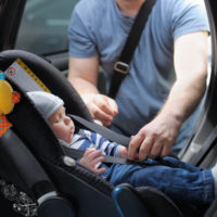 Father-straping-baby-in-car-seat